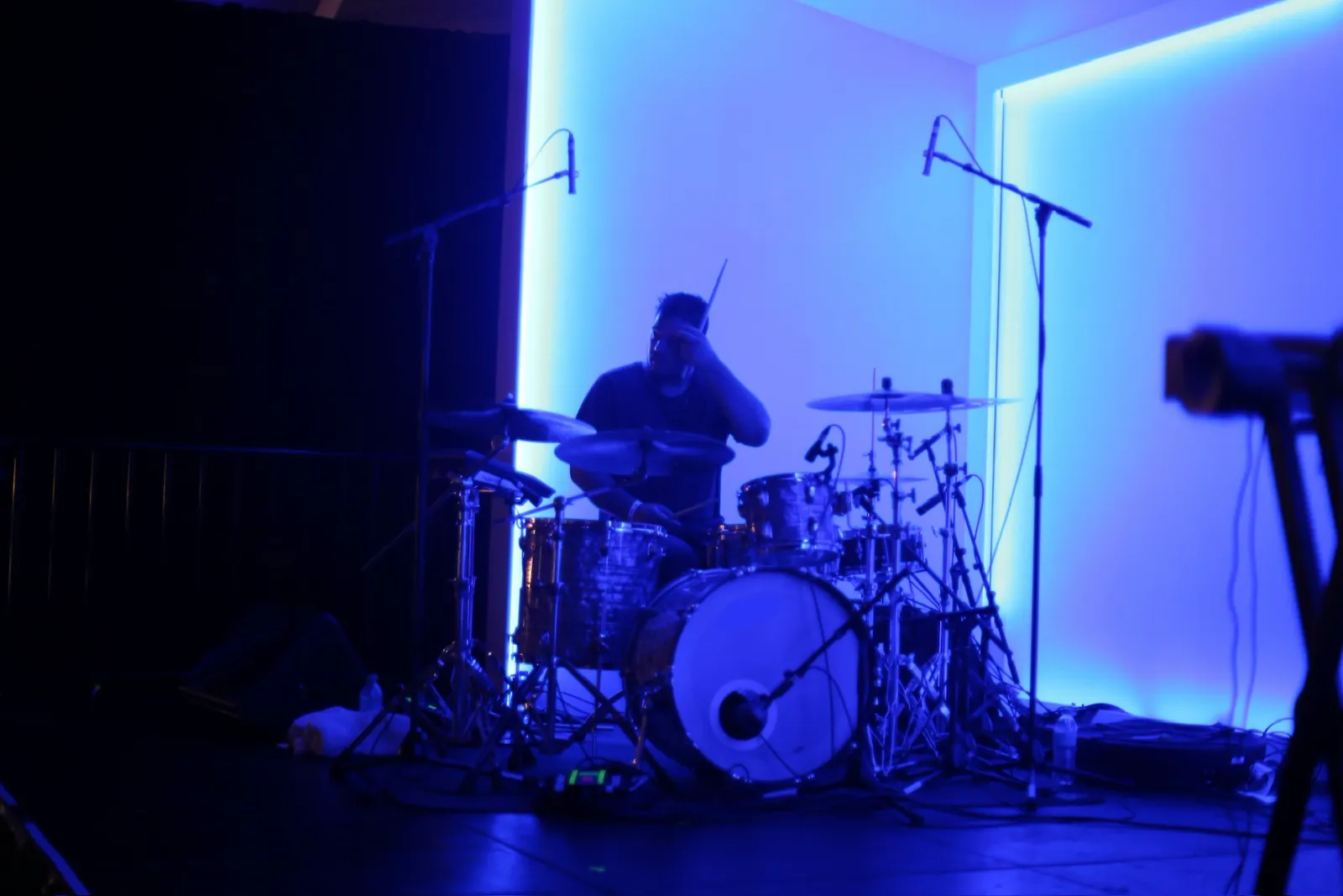 Anthony achter een drumstel in blauw podiumlicht