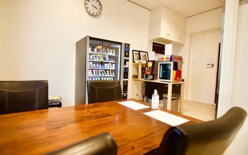 Lounge bij Silver Note Studios met snackautomaat, koelkast en een grote houten tafel